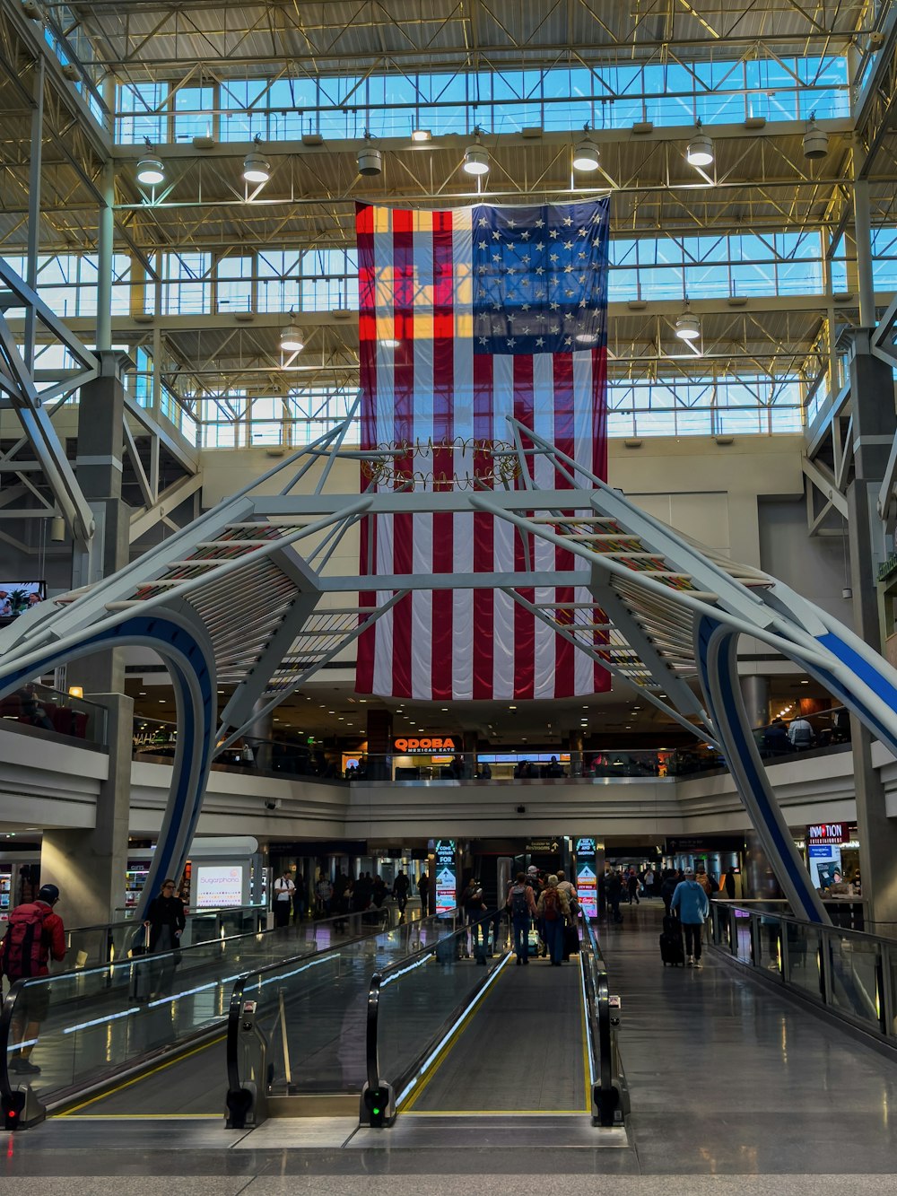 a large american flag hanging from the ceiling of an airport