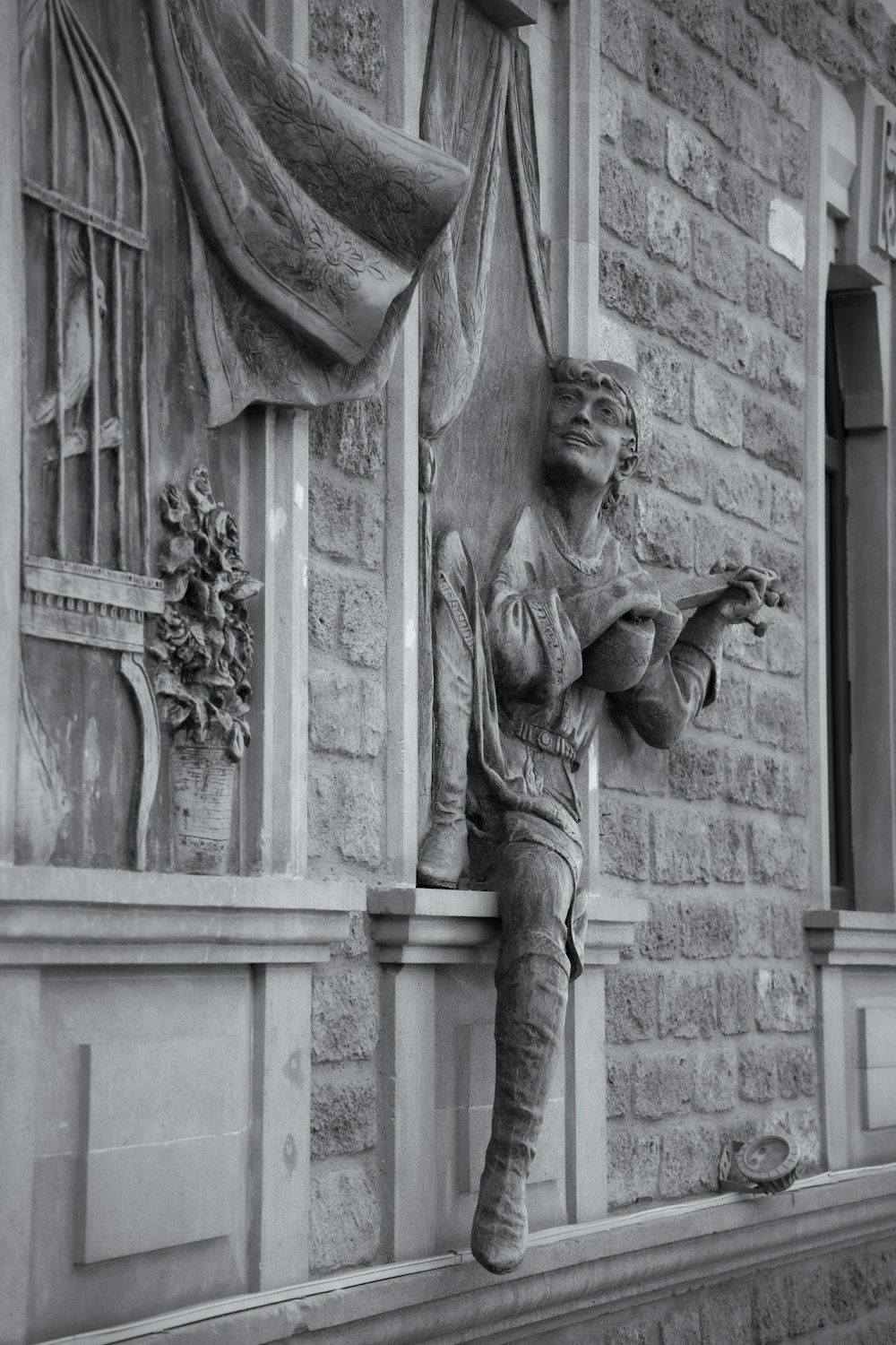 a statue of a woman sitting on a window sill