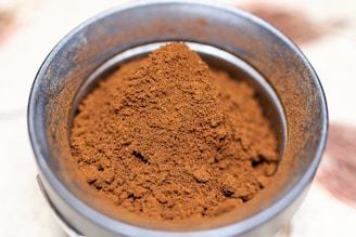 a metal bowl filled with red powder on top of a table