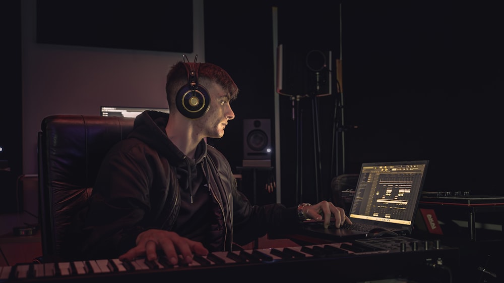 a man wearing headphones sitting in front of a keyboard