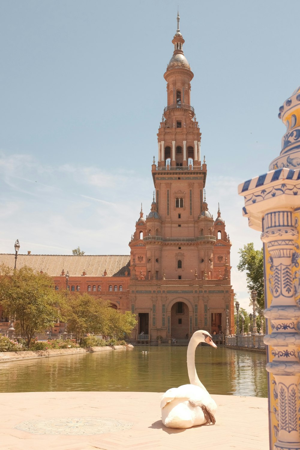 a white swan sitting on the ground in front of a building