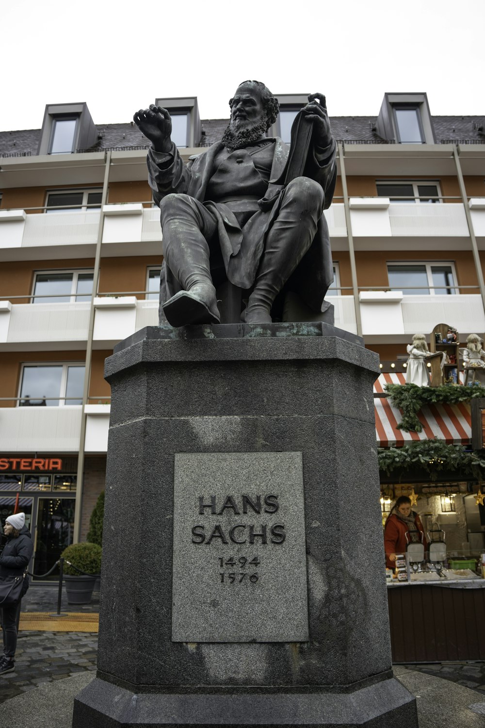 a statue of a man holding a book in front of a building