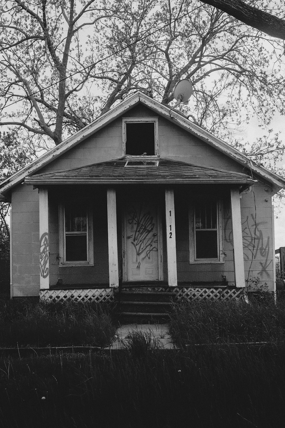 a black and white photo of a house with graffiti on it