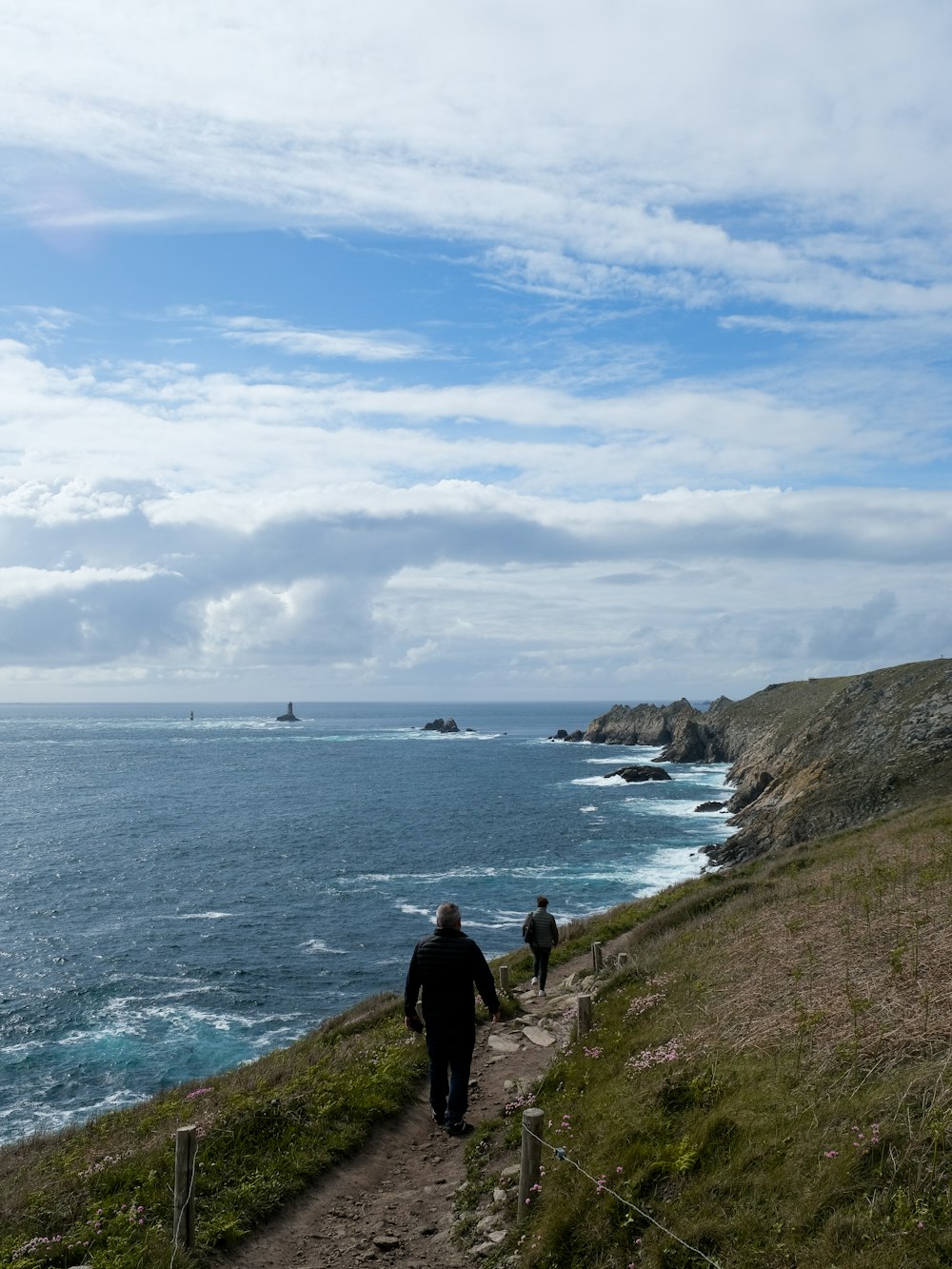 a man walking down a path next to the ocean