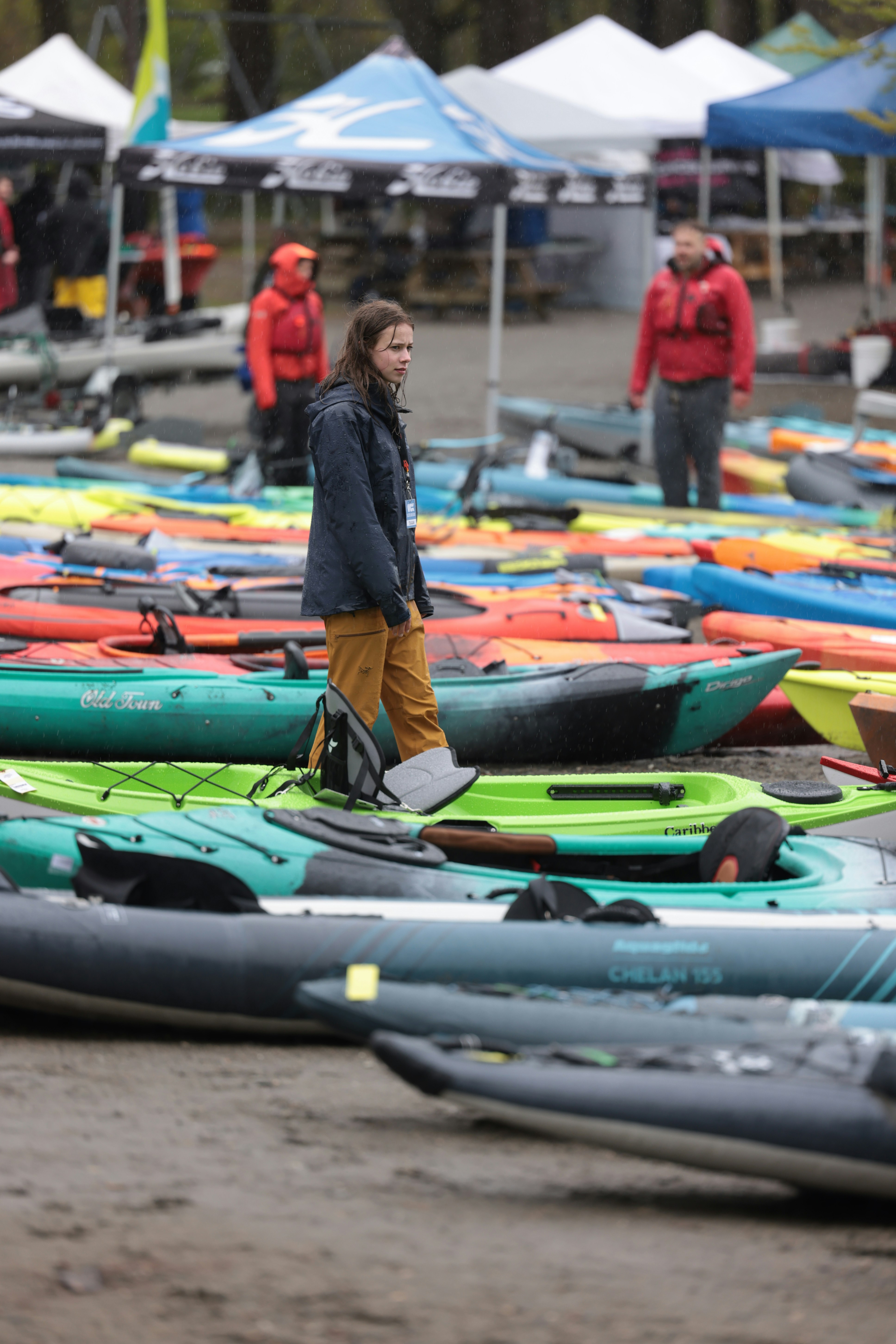 una donna in piedi davanti a un mucchio di kayak