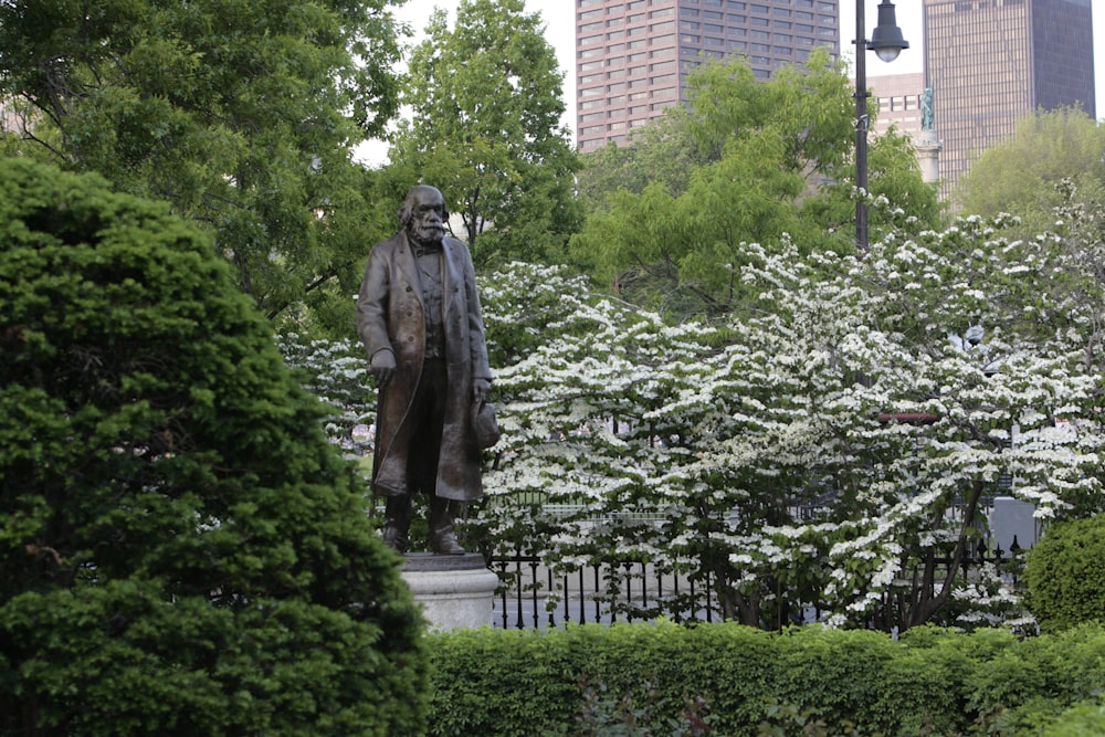 a statue of a man in a park surrounded by trees