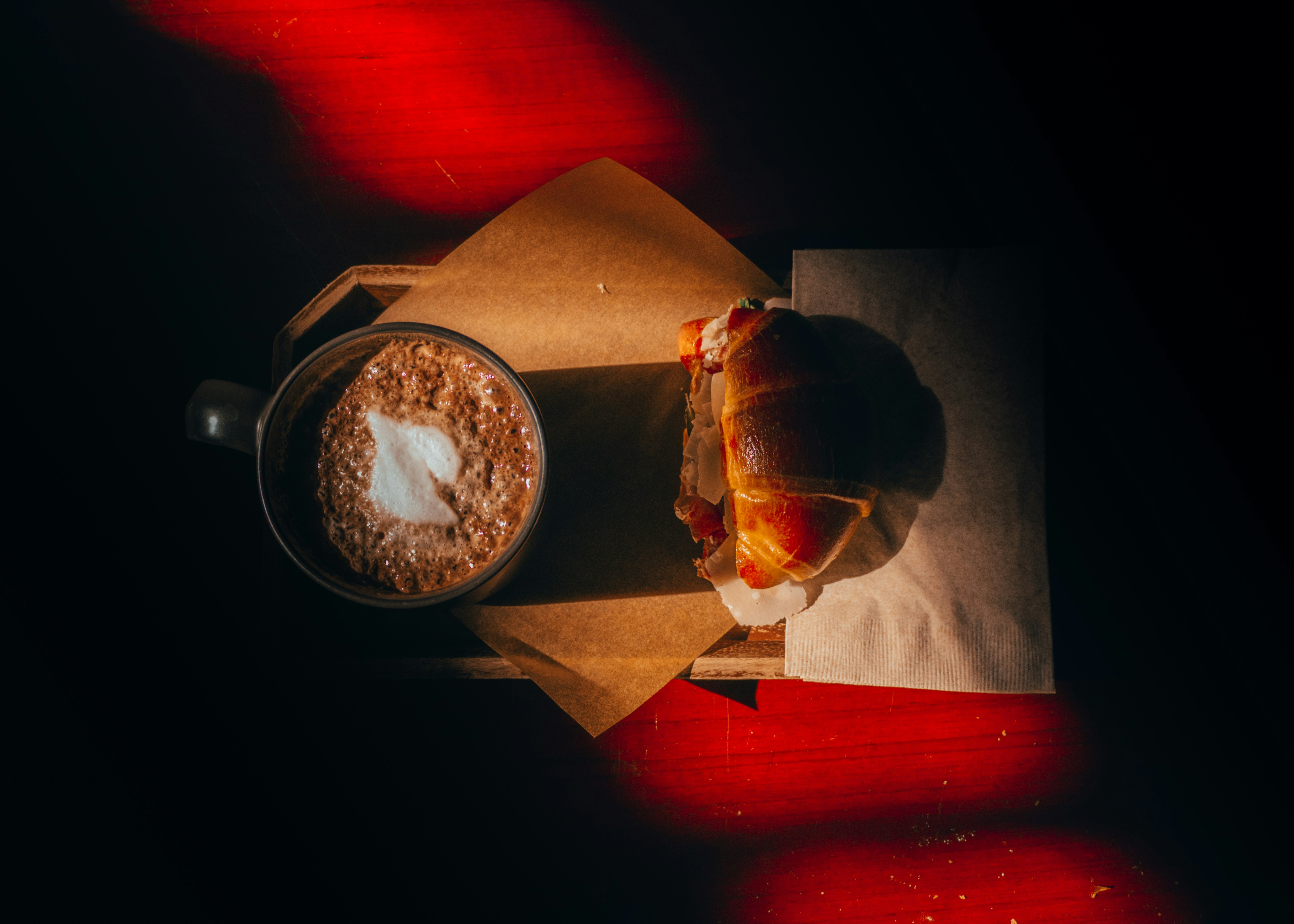 Overhead latte and pastry in red light