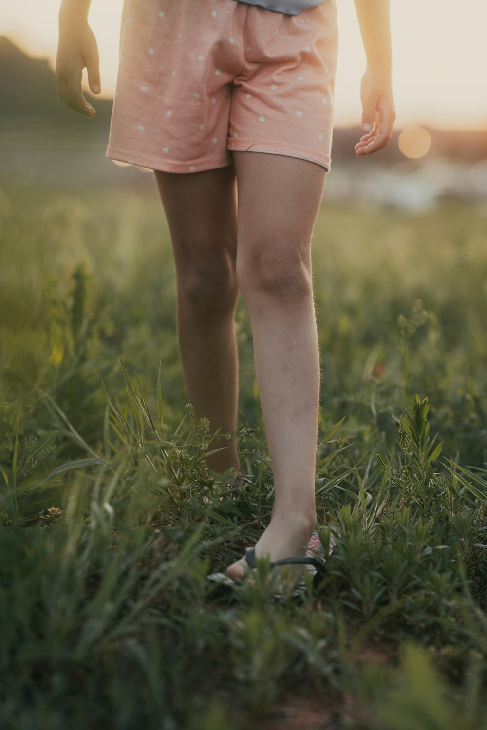 une petite fille debout dans un champ d’herbe