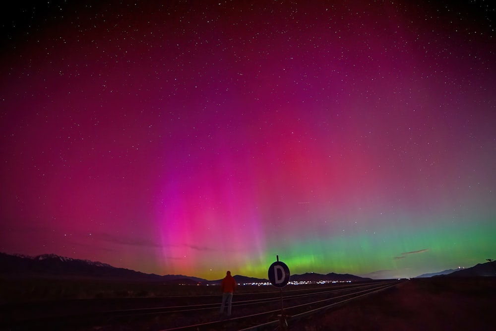 a person standing on a train track under a colorful sky