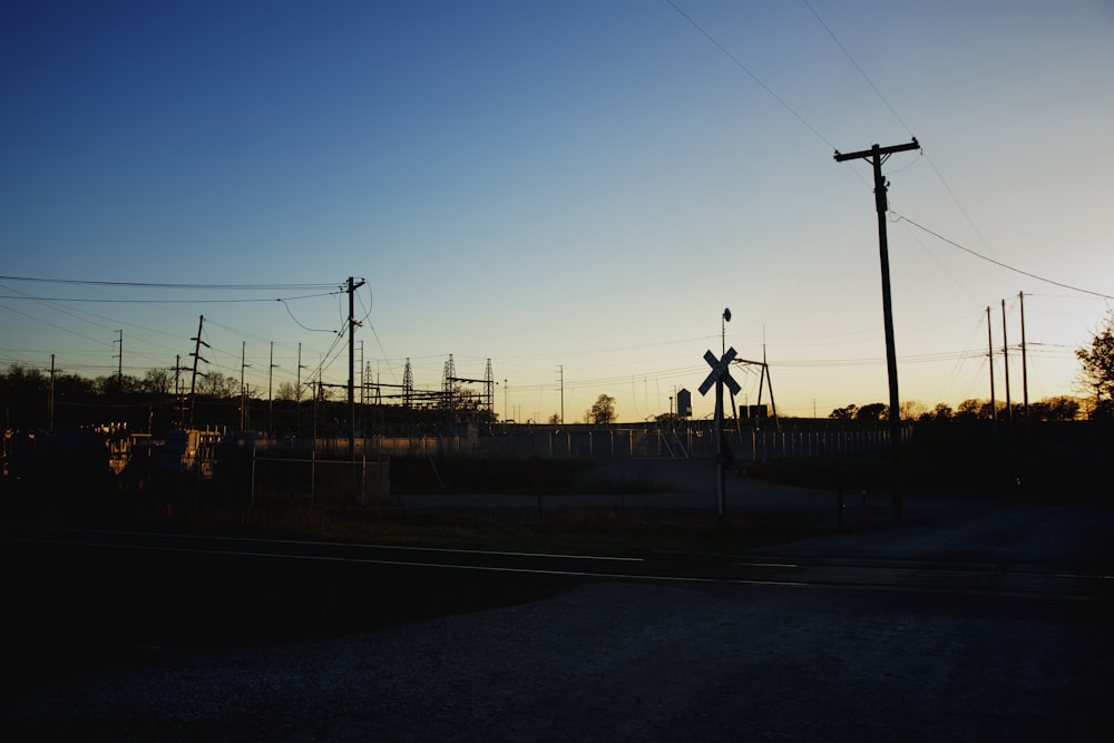 the sun is setting behind a railroad crossing