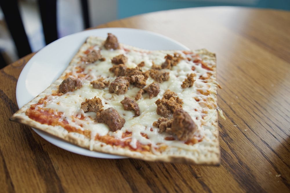 un plato blanco cubierto con una pizza encima de una mesa de madera