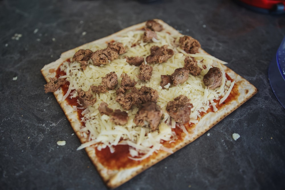 a square pizza with meatballs and cheese on it