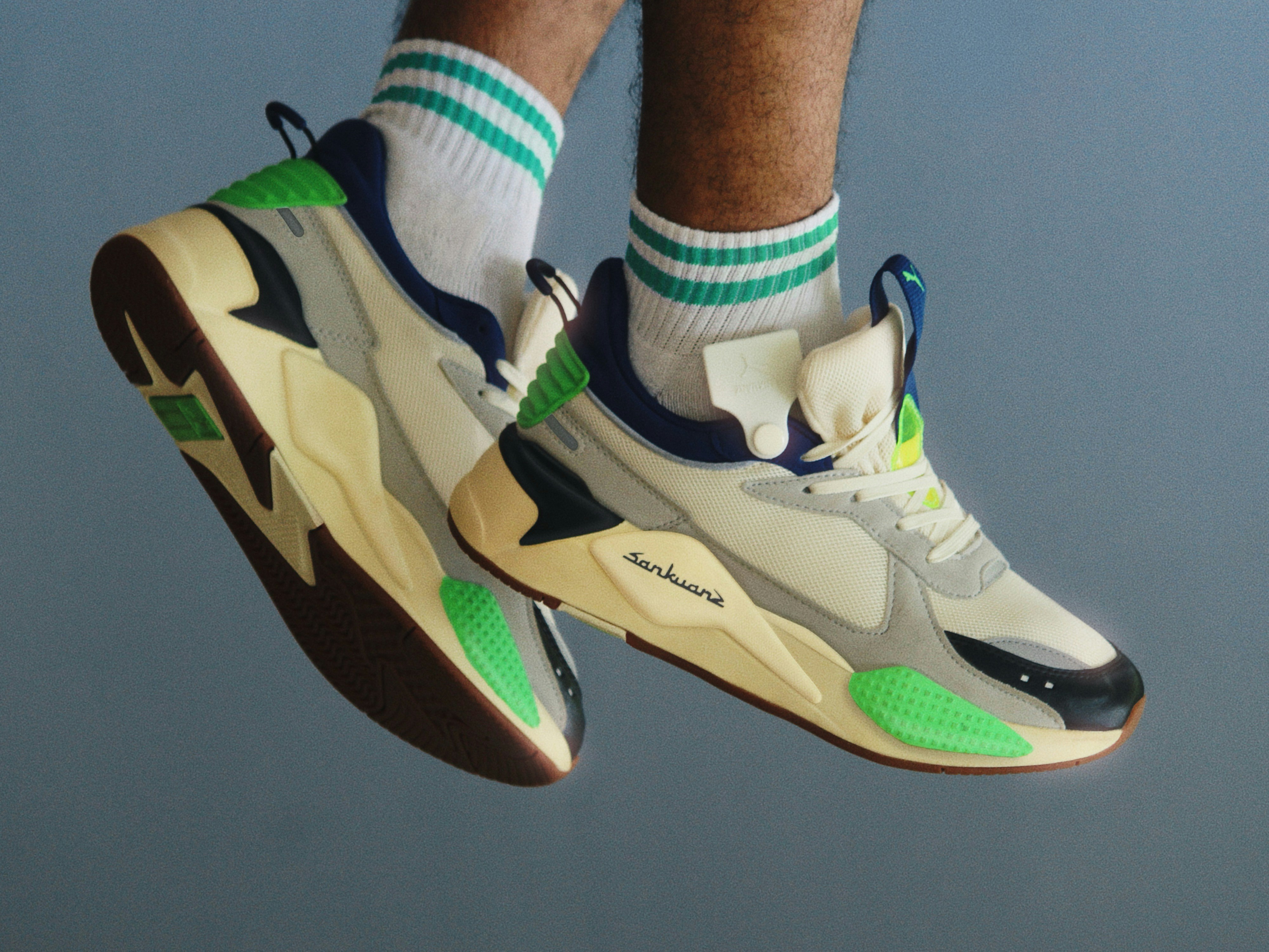 a person wearing a pair of white and green sneakers