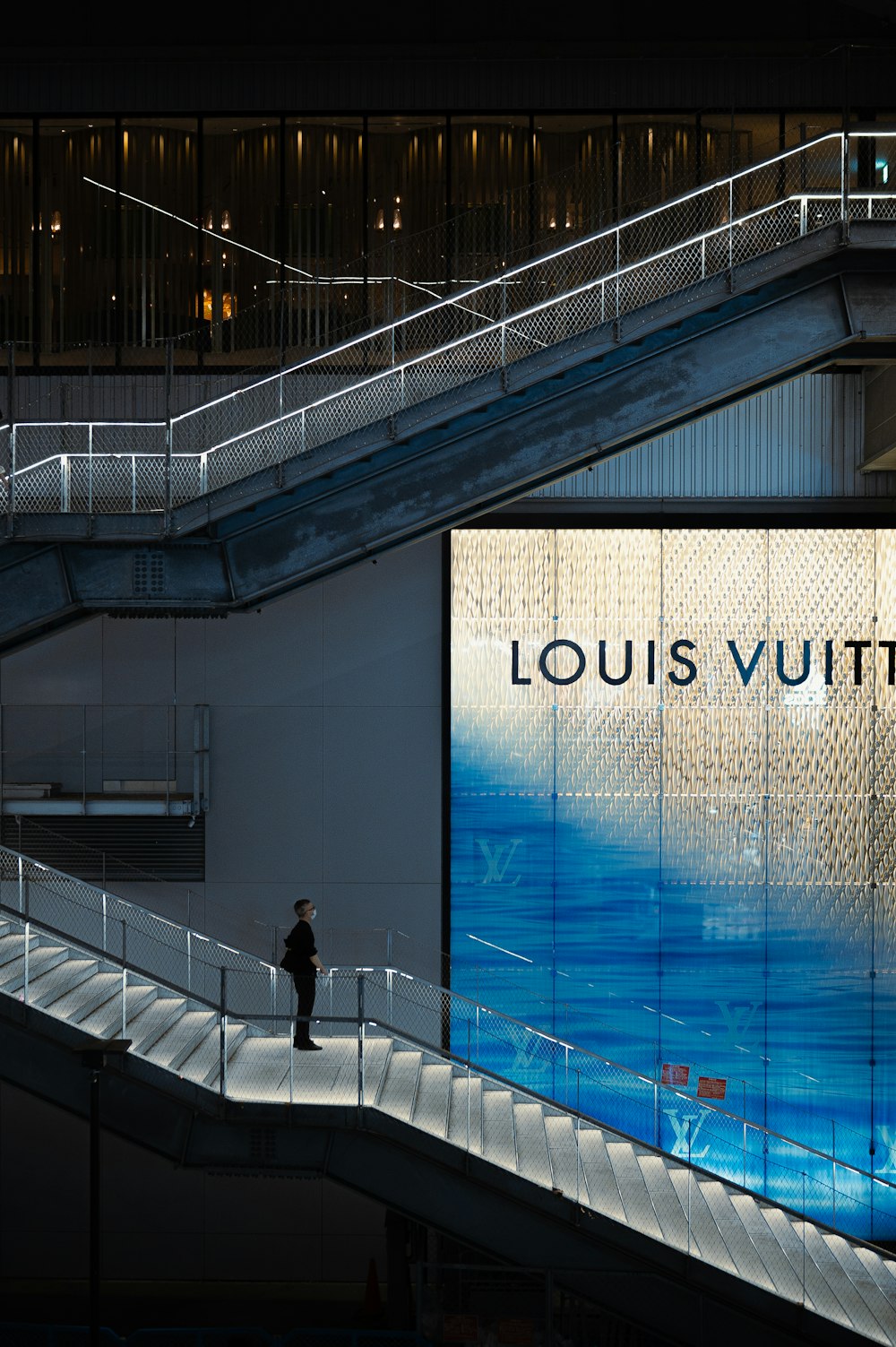 a man is standing on a escalator in front of a louis vuitt