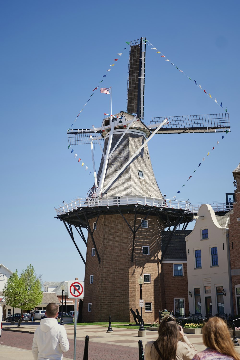 a group of people walking down a street next to a windmill