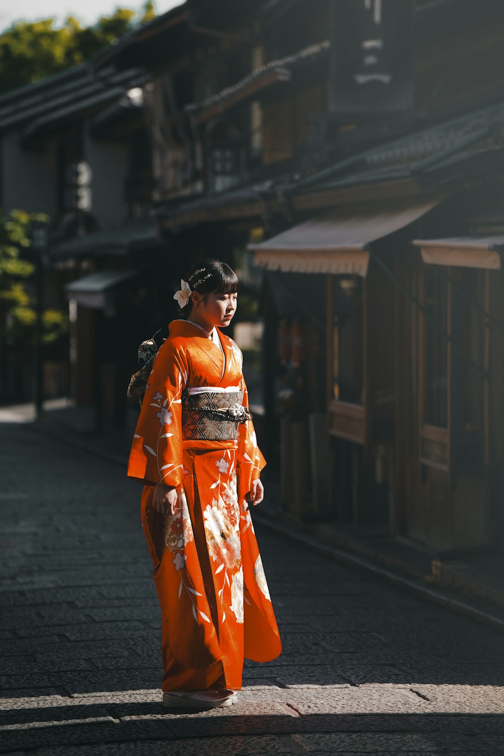 a woman in an orange kimono walking down a street