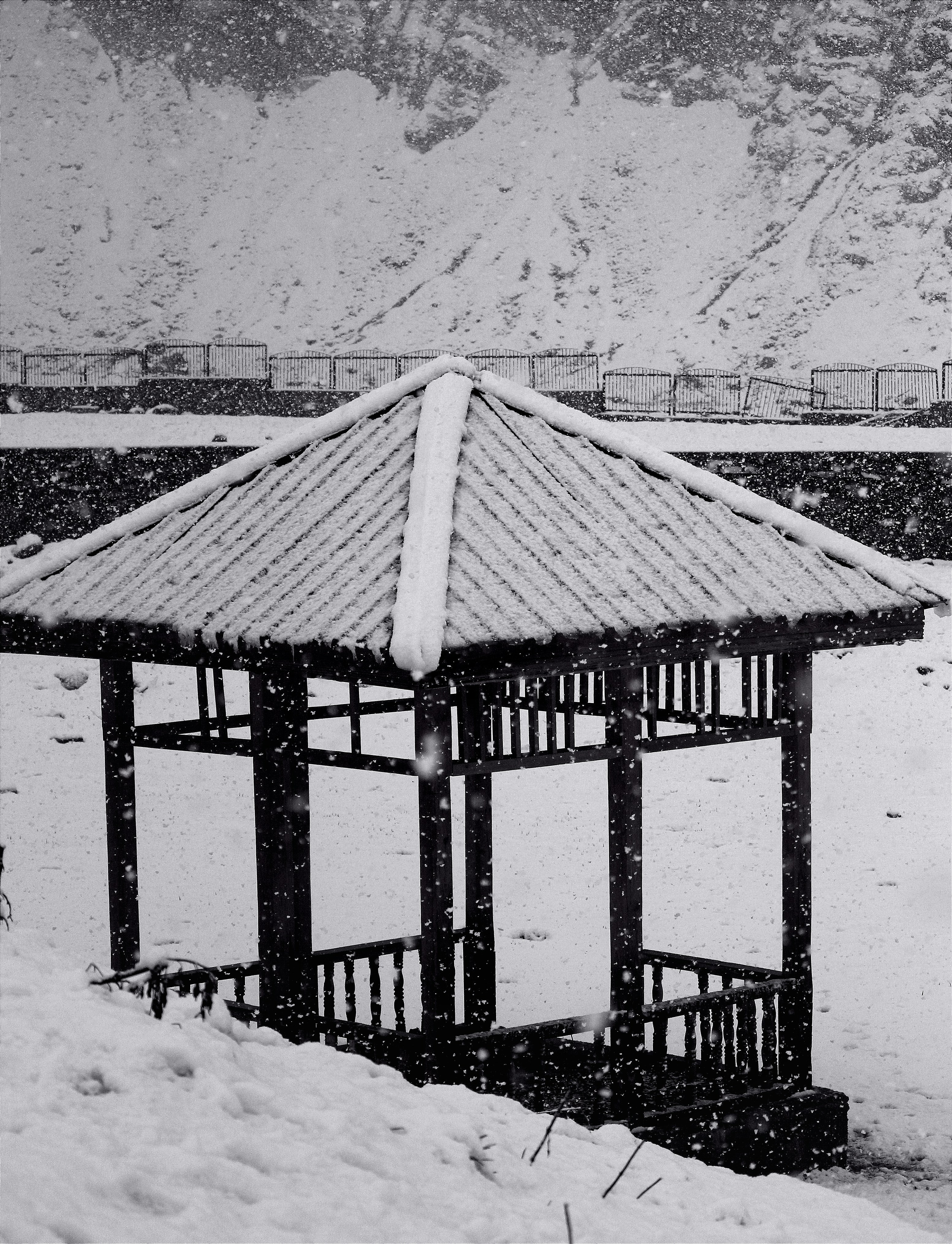 a gazebo in the snow with mountains in the background
