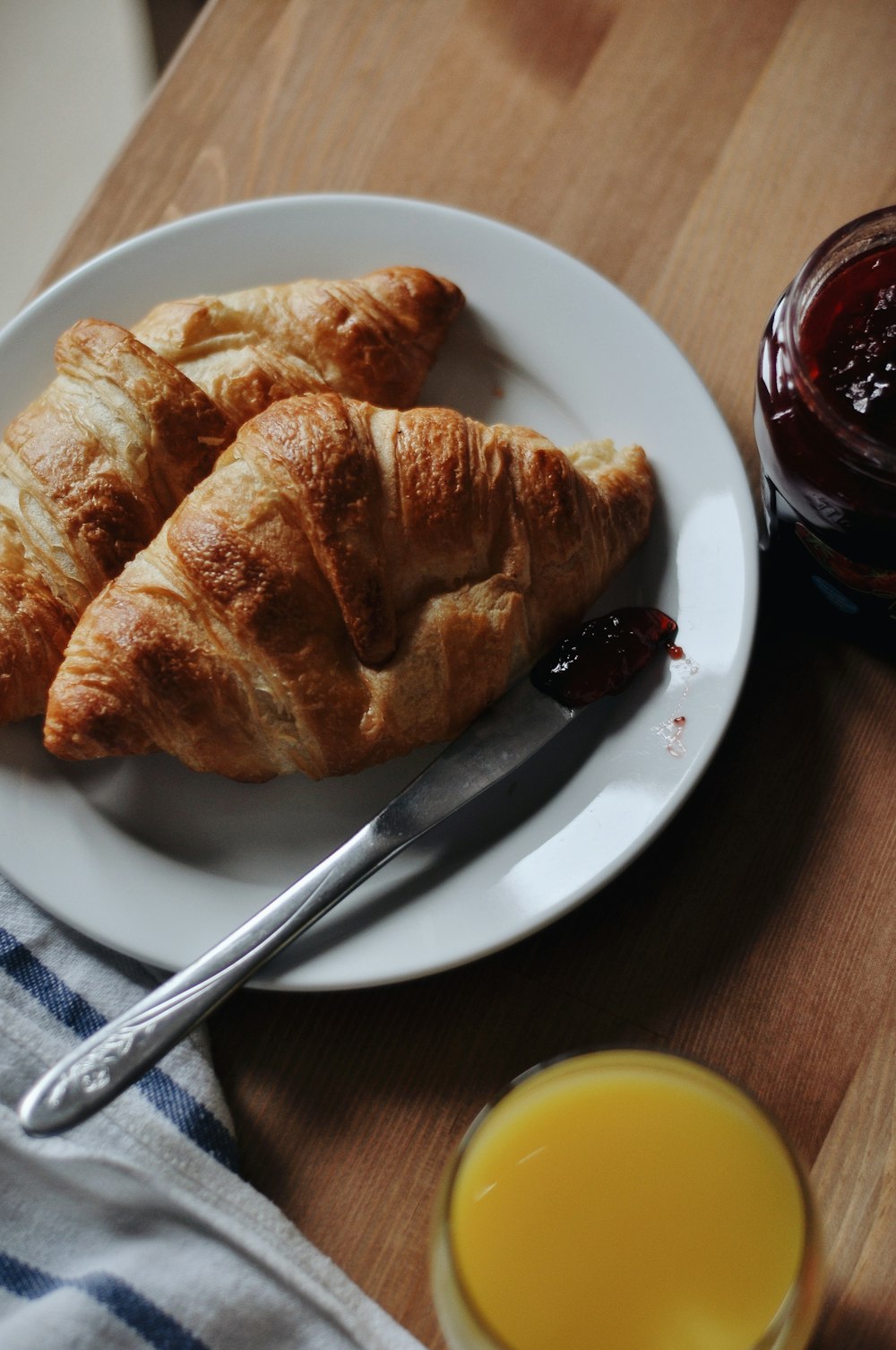 a white plate topped with croissants next to a glass of orange juice