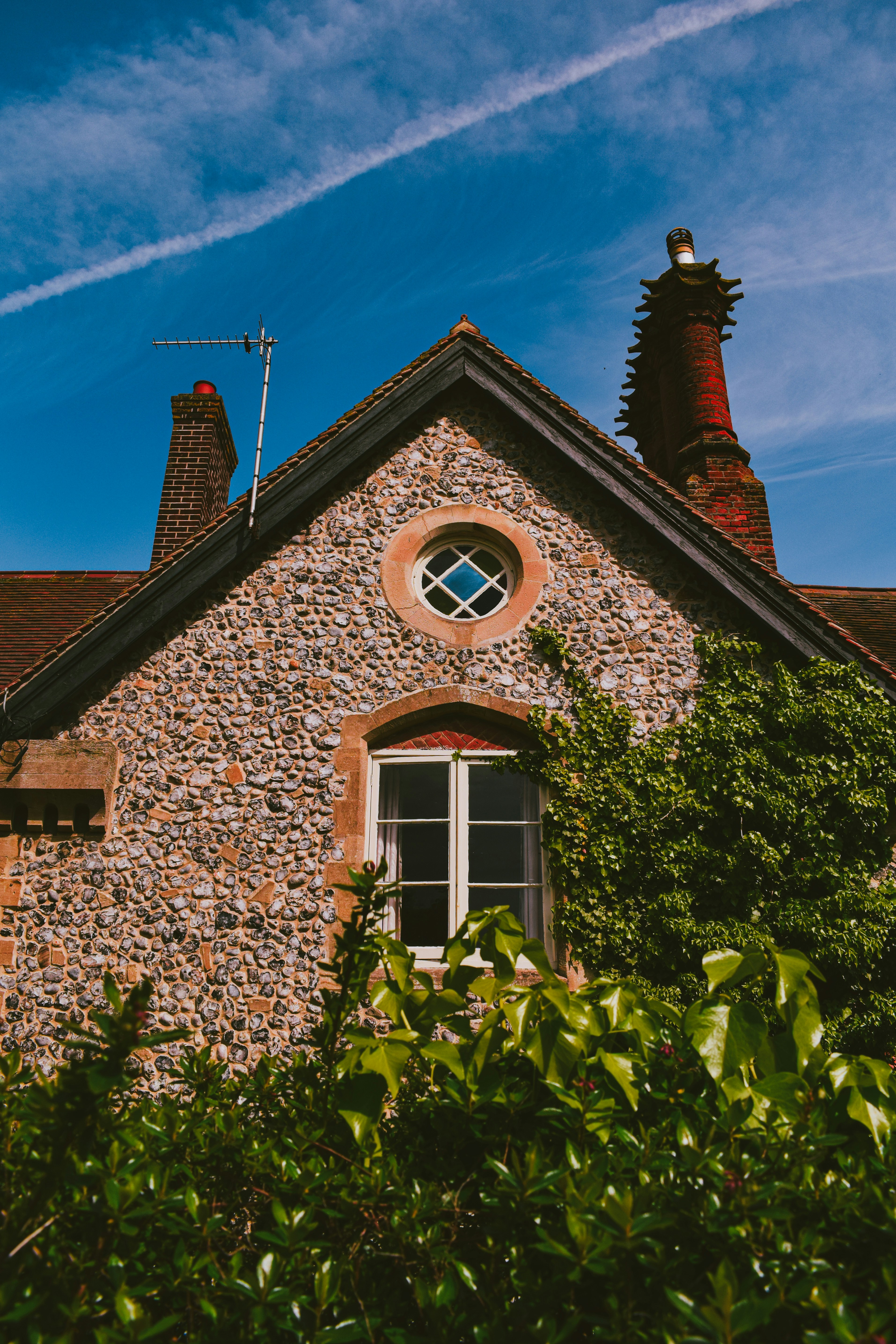 a stone building with a round window surrounded by greenery
