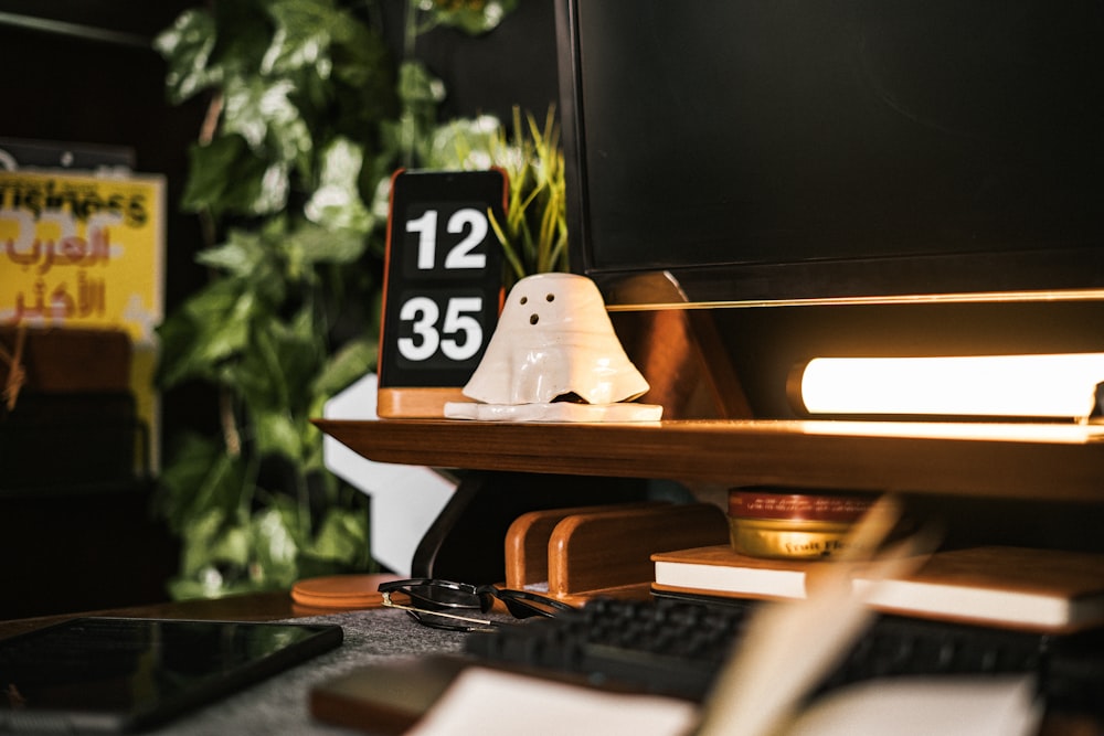 a desk with a computer and a ghost figurine on it