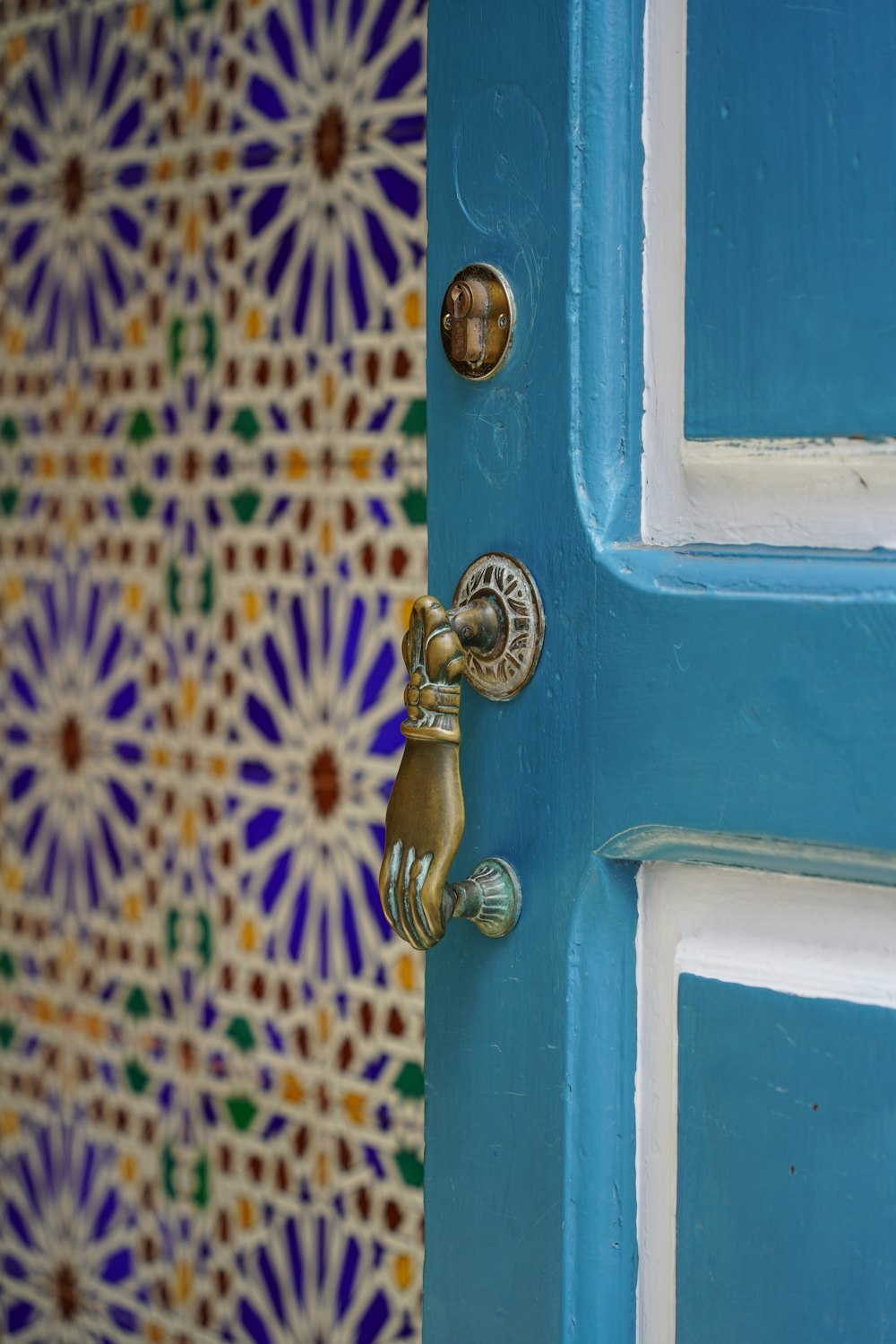 un gros plan d’une poignée de porte sur une porte bleue