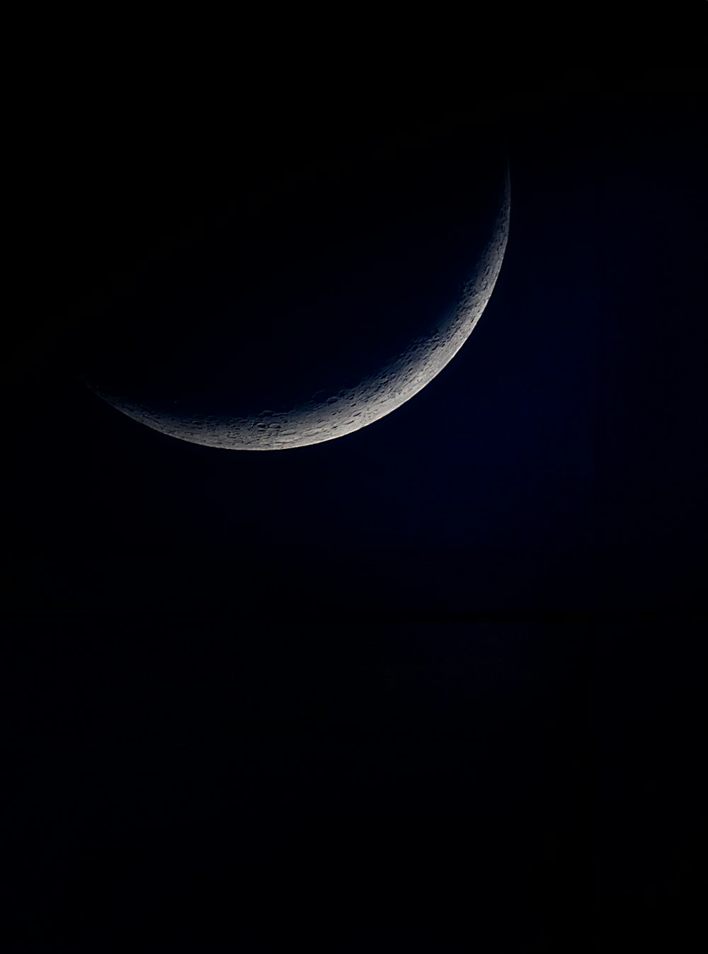 a crescent moon is seen in the dark sky