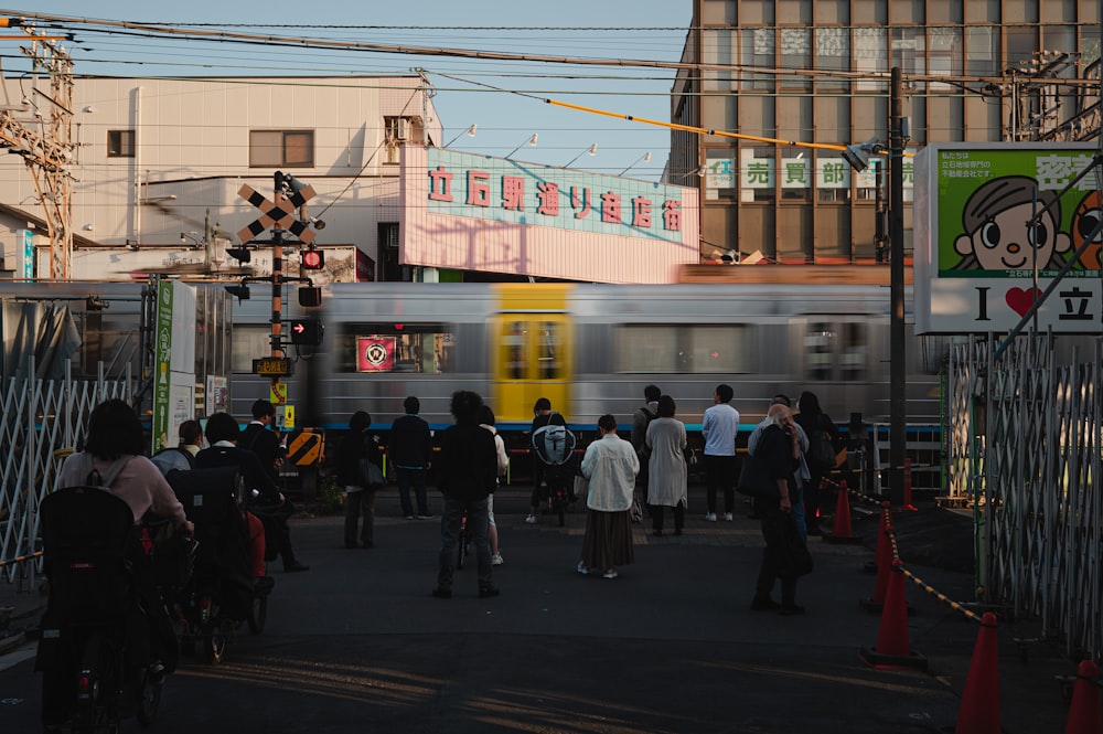 a group of people standing on the side of a road next to a train