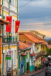 a city street lined with tall buildings with red flags