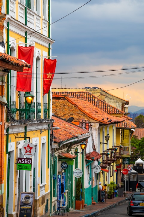 a city street lined with tall buildings with red flags