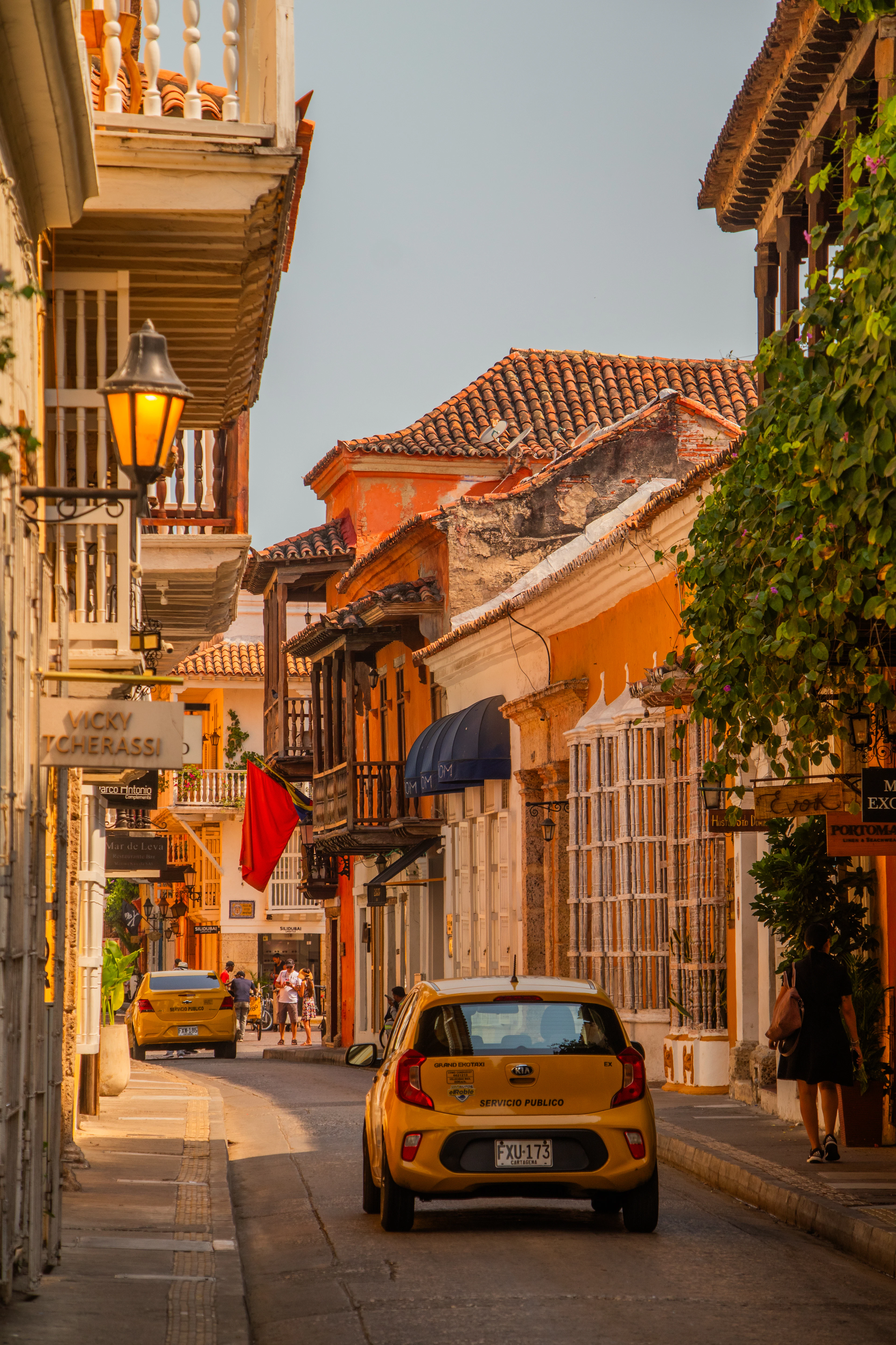A lit street lamp and yellow taxis line a golden-hour street in Cartagena's walled city.