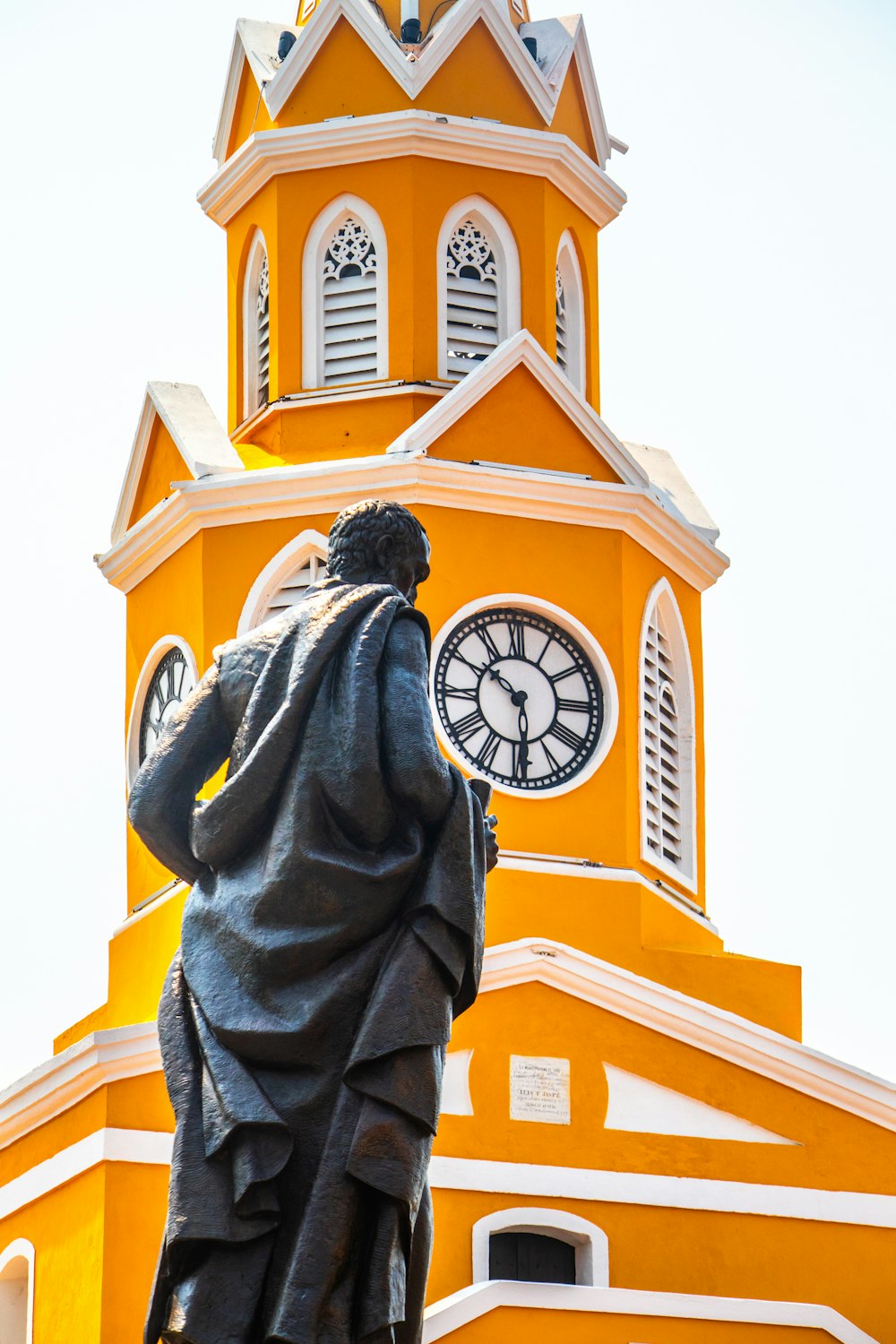 a statue of a man standing in front of a clock tower