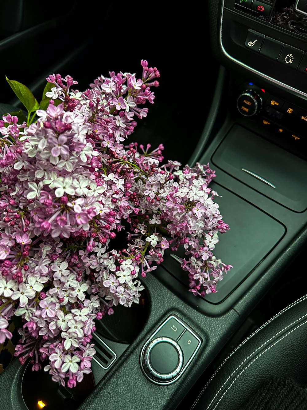 a bunch of purple flowers sitting in a cup holder in a car
