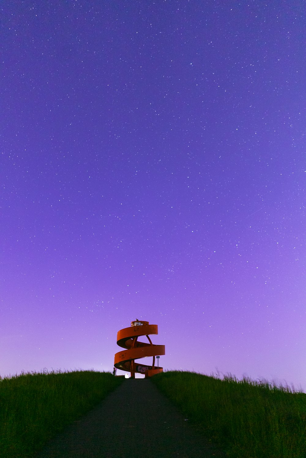 a bench sitting on top of a hill under a purple sky