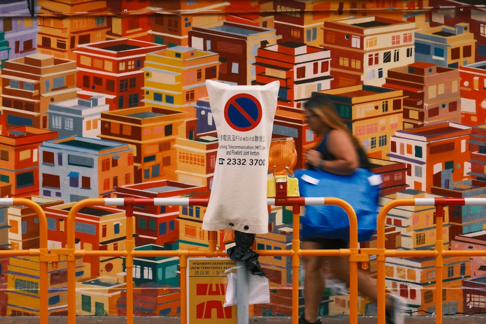 a woman in a blue dress is walking past a wall of colorful houses