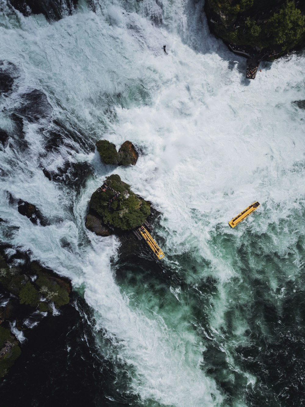 a yellow raft floating down a river next to a lush green forest