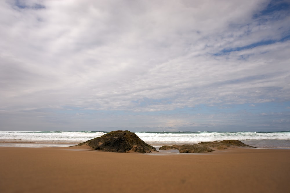 a sandy beach next to the ocean under a cloudy sky