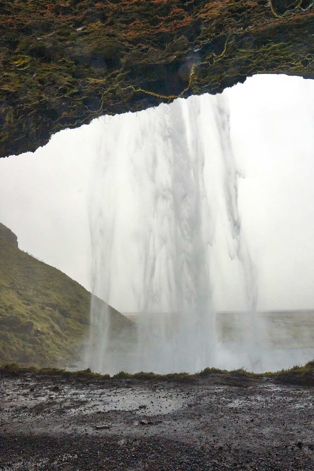 a view of a waterfall through a hole in the ground