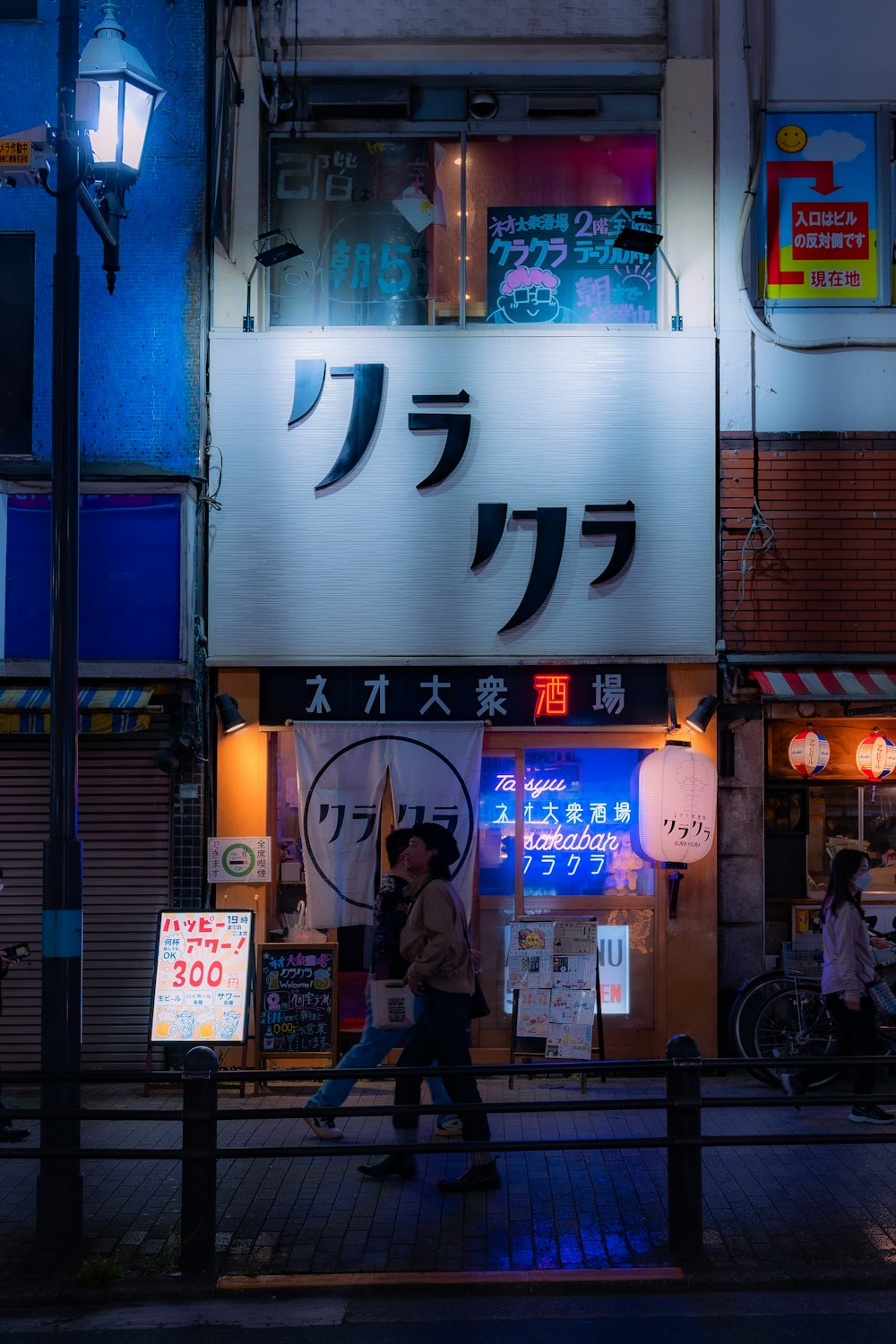 a couple of people walking down a street at night