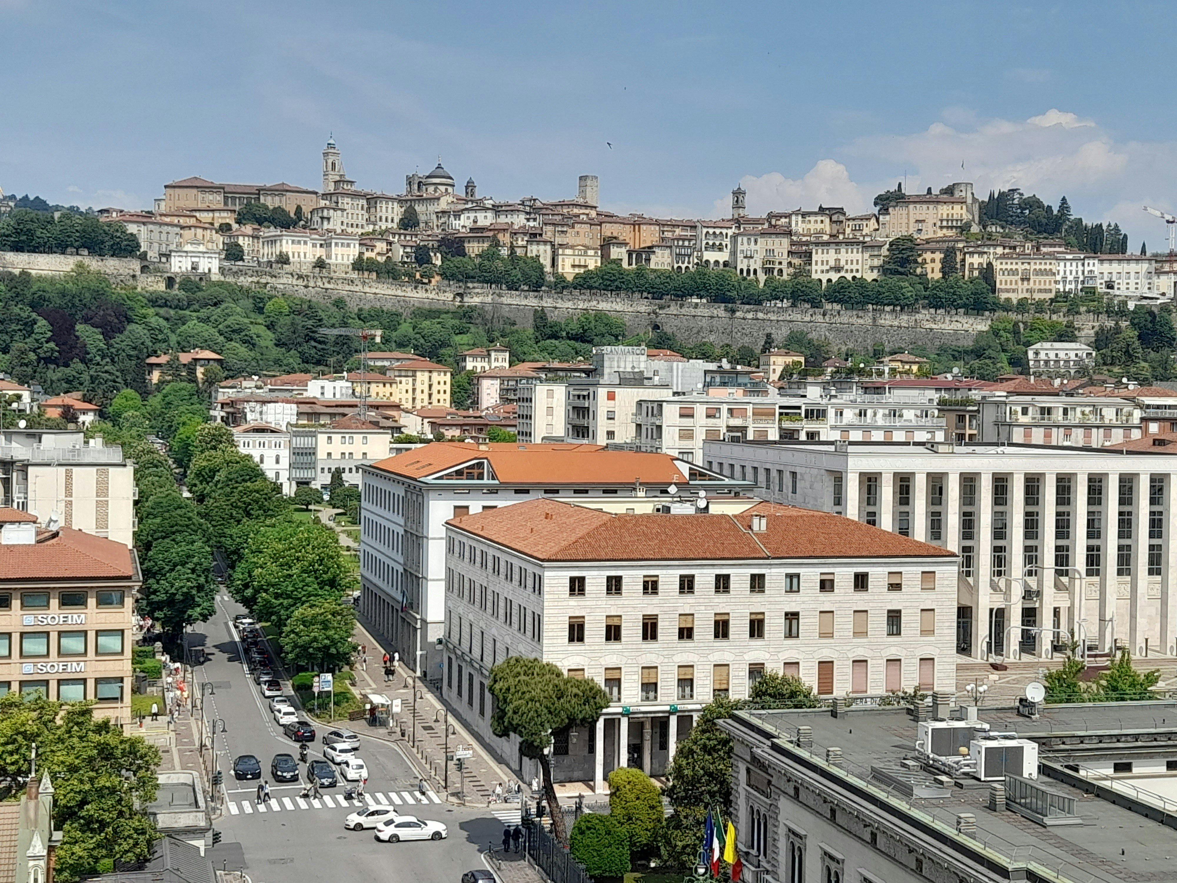 Cazare în Bergamo: clădirile din Città Bassa, cu orașul de sus pe deal în spate