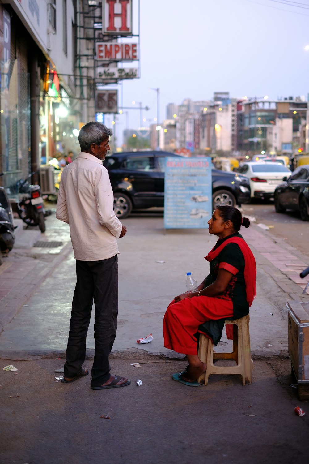 a man standing next to a woman sitting on a bench