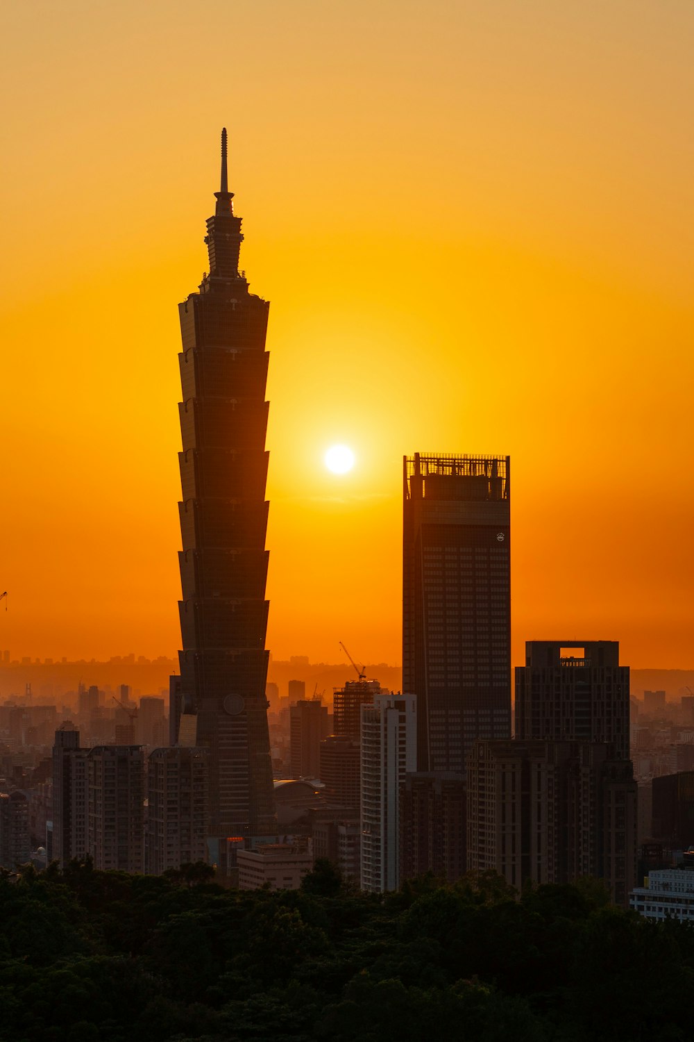 the sun is setting over a city with tall buildings