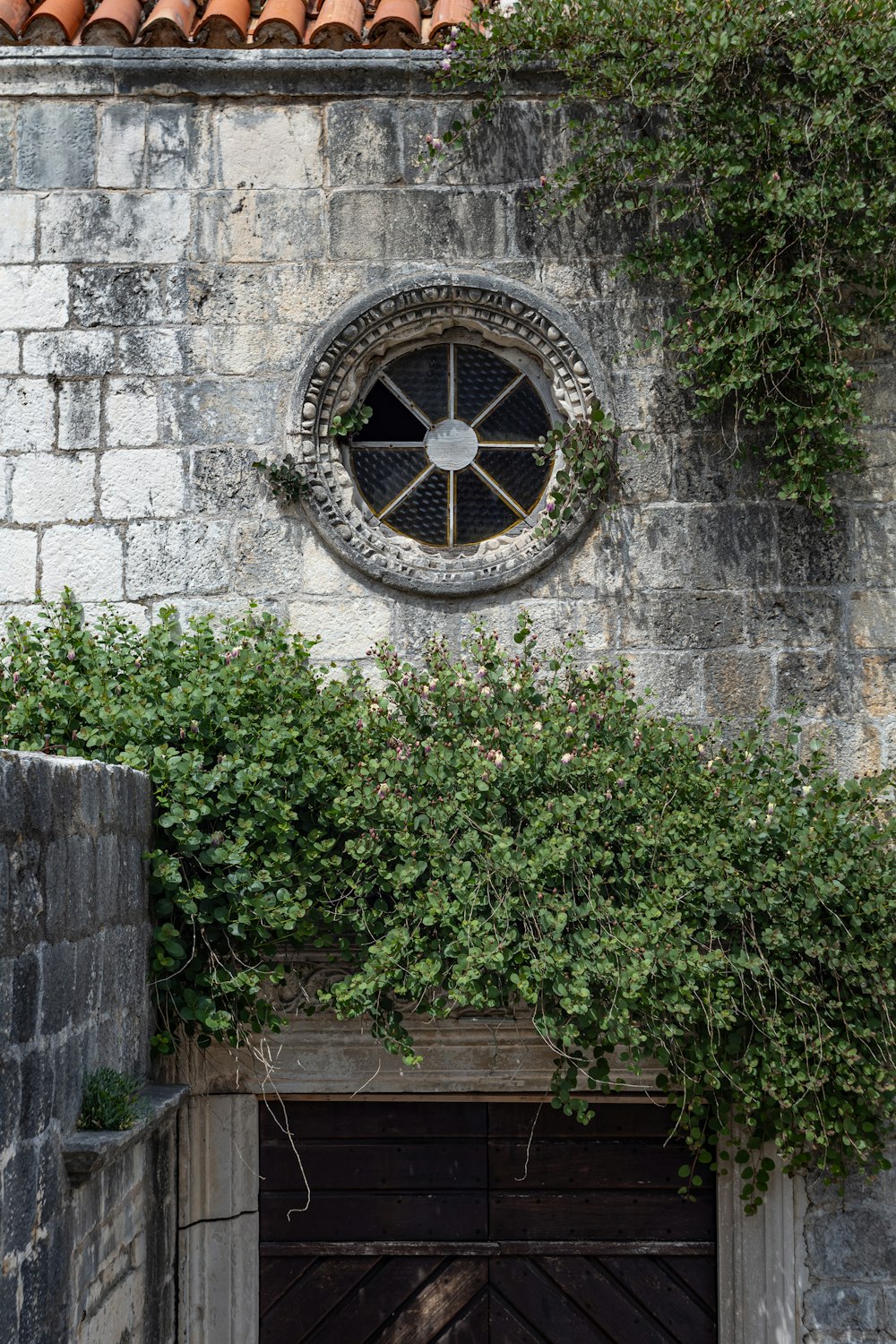 a stone building with a round window and ivy growing up the side of it