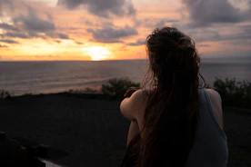 a woman sitting on a bench looking out at the ocean