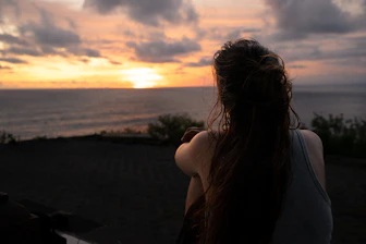 a woman sitting on a bench looking out at the ocean