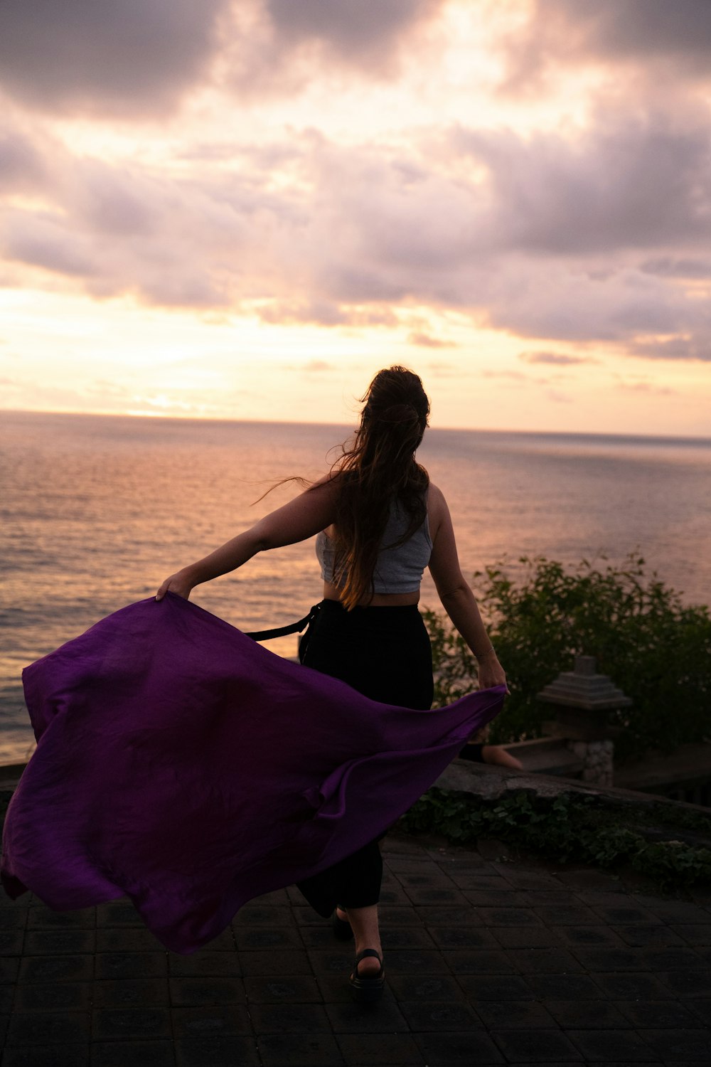 a woman with a purple scarf is walking by the ocean
