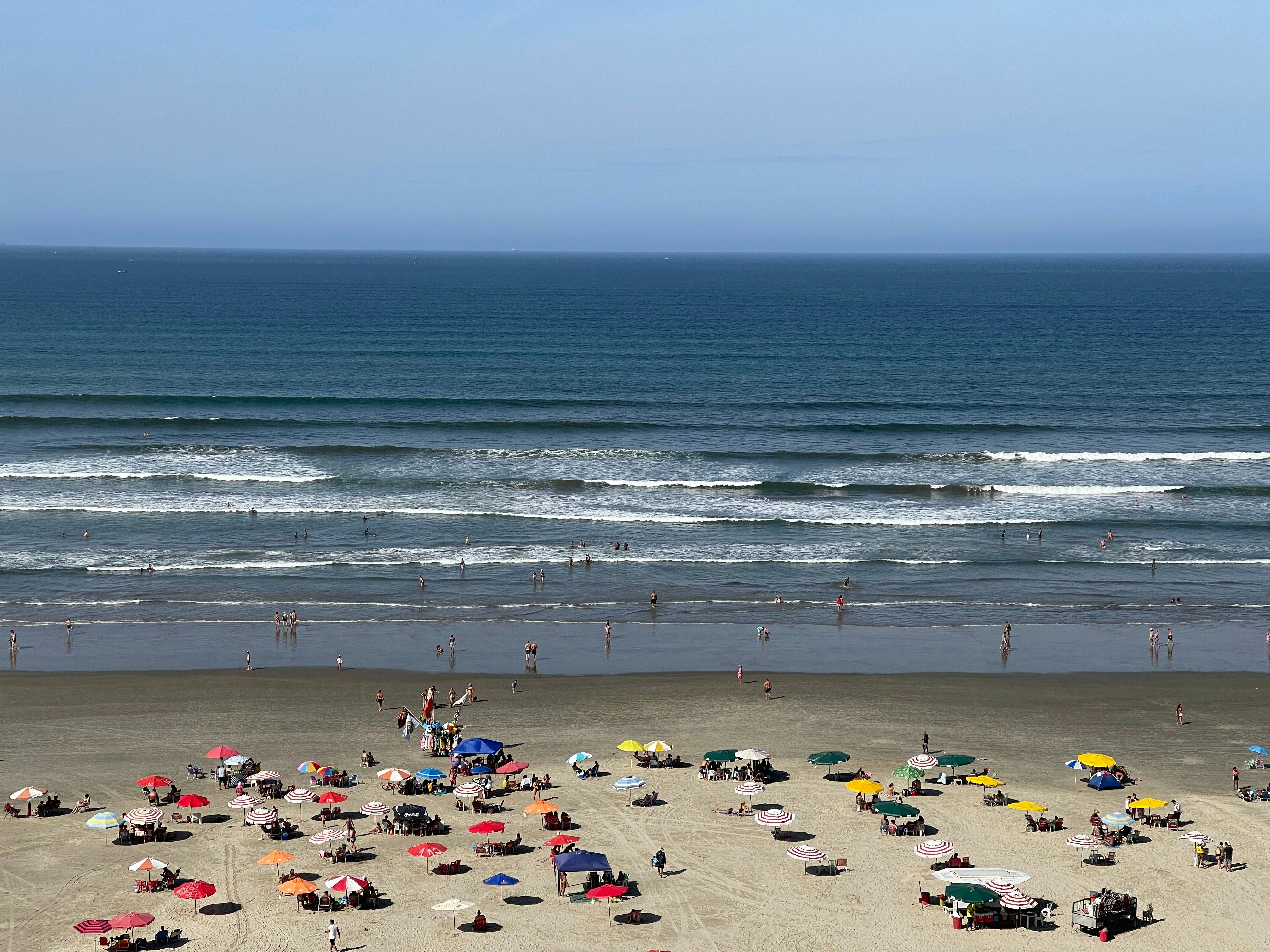 Travelers relaxing on Ganpatipule beach with beach umbrellas and clear sky
