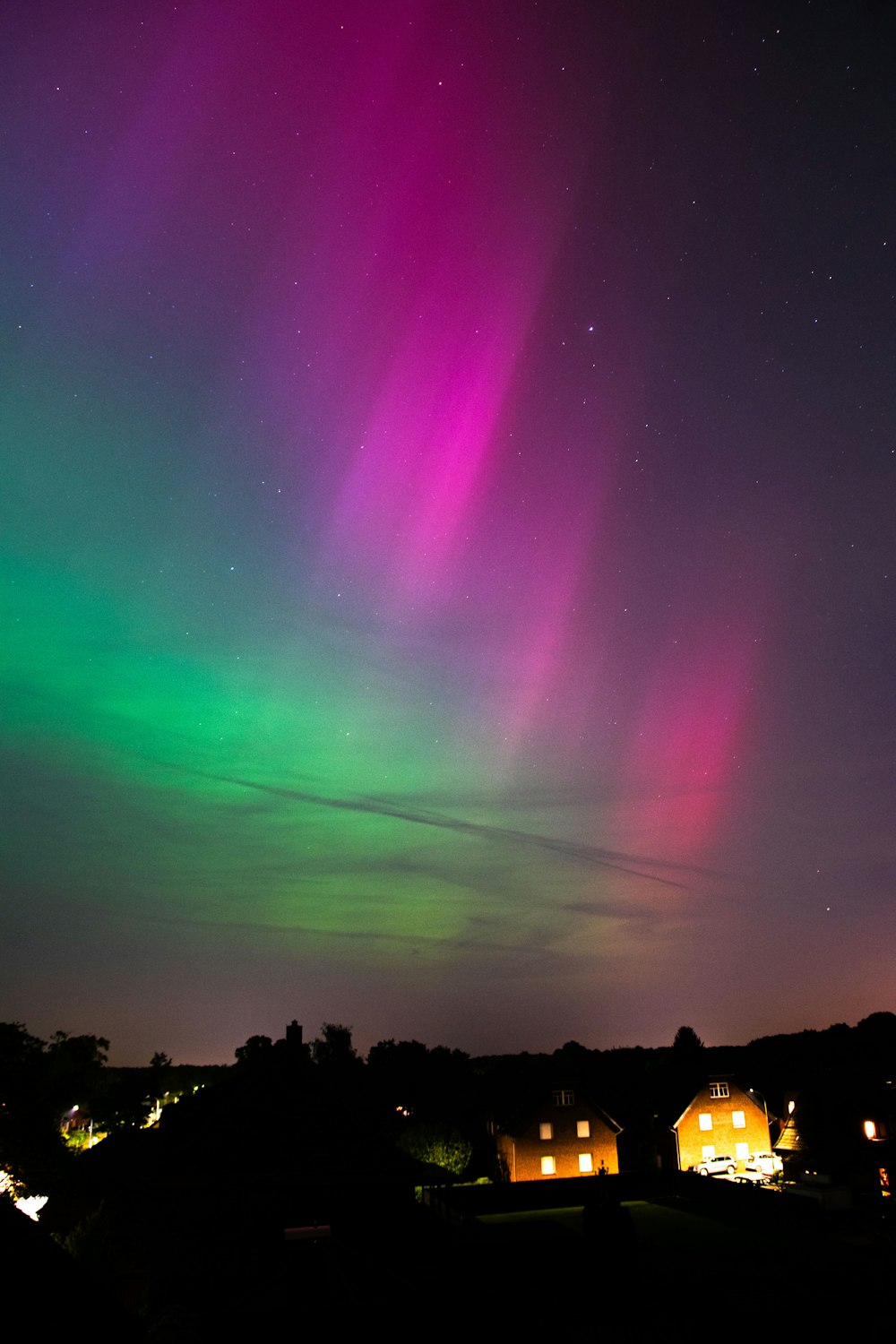 the aurora bore in the night sky over houses