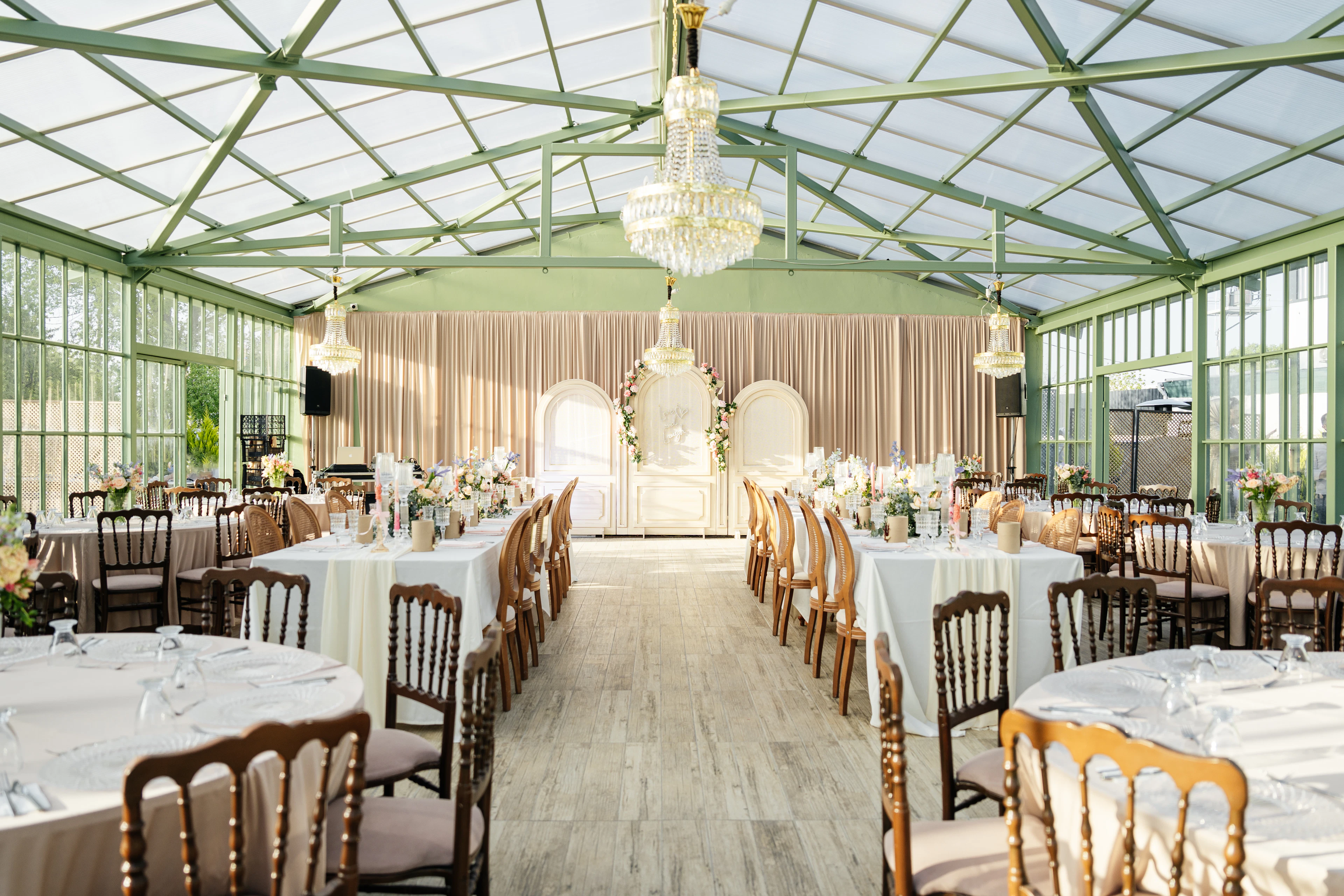 Glass conservatory set with round tables for a wedding reception
