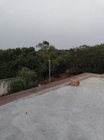an empty concrete parking lot with trees in the background