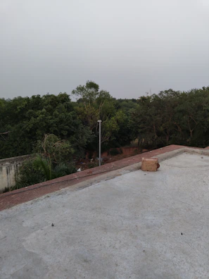 an empty concrete parking lot with trees in the background